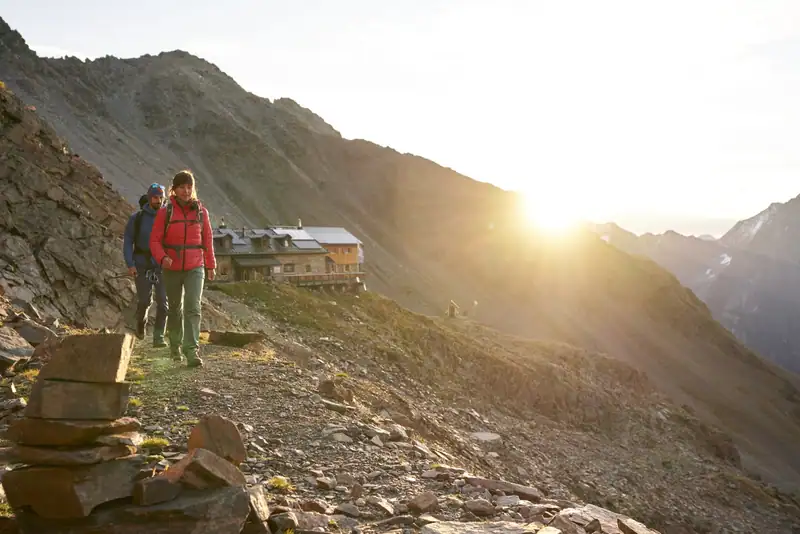 Wanderpaar vor einer Schutzhütte im Morgenlicht